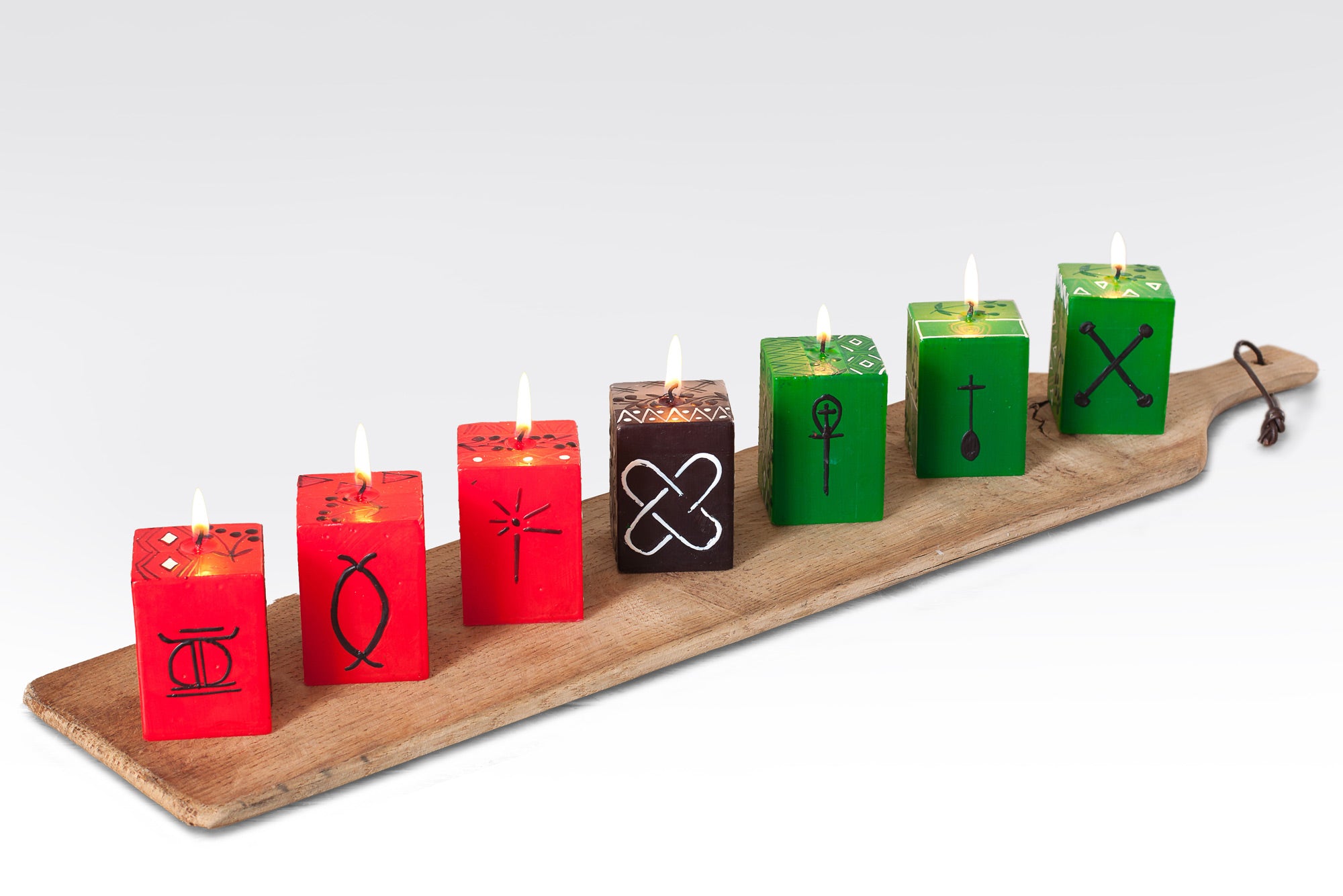 Kwanzaa hand made & hand painted cube candles collection. Three 2x2x3 cube red candles, one 2x2x3 cube black candle and three 2x2x3 cube green candles. Each has a different Kwanzaa symbol on the front & back with a flower pattern down the side. Fair Trade home decor.