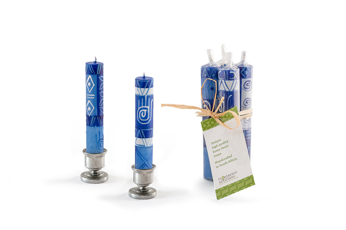 A pair of Hamsa blue & white Shabbat candles in pewter taper holders, with a pack of 4 tied together with a story card showing how these candles are sold in a gift pack.