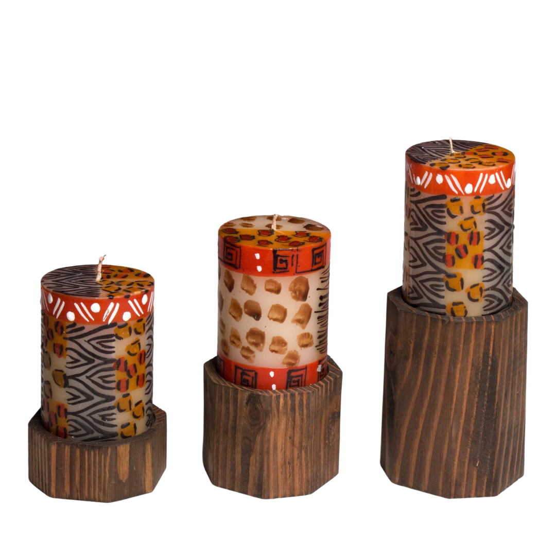 Three 3"x4" pillar candles in Animal Prints on top of brown wood pillar candle holders in three different heights..  Fair Trade.