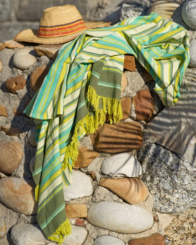 Seaween Kikoi draped on some rocks with a straw hat beside the wrap.  