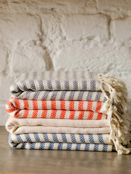 Stack of Turkish towels with stripes.  In colors of grey/white, red/white, soft pink/white, blue/white.