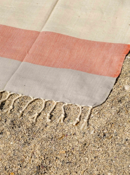 Linen Blend Turkish Towel laid out on the ground showing the tie tassels on the edge.  Grey stripe, rust red stripe, and cream.