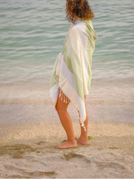 Woman on the beach wrapped in the lime green & cream striped Turkish towel.