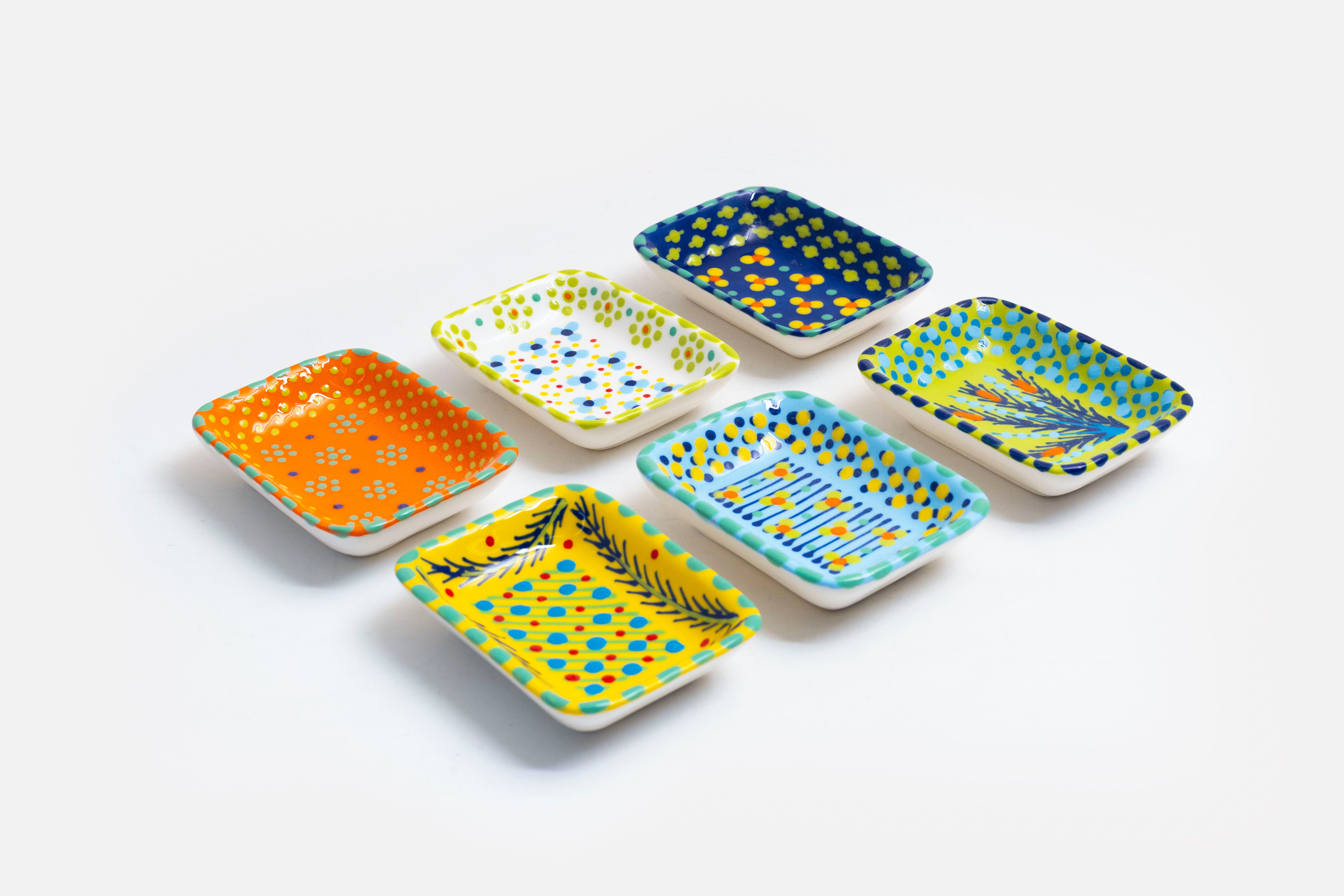 Ceramic rectangle shape Tiny Dishes  with base colors of orange, white, indigo blue, yellow, baby blue an lime green. Dots, Stripes and flowers painted on top in yellow, red, blue and jasper green.  Great as a trinket dish or for side condiments.