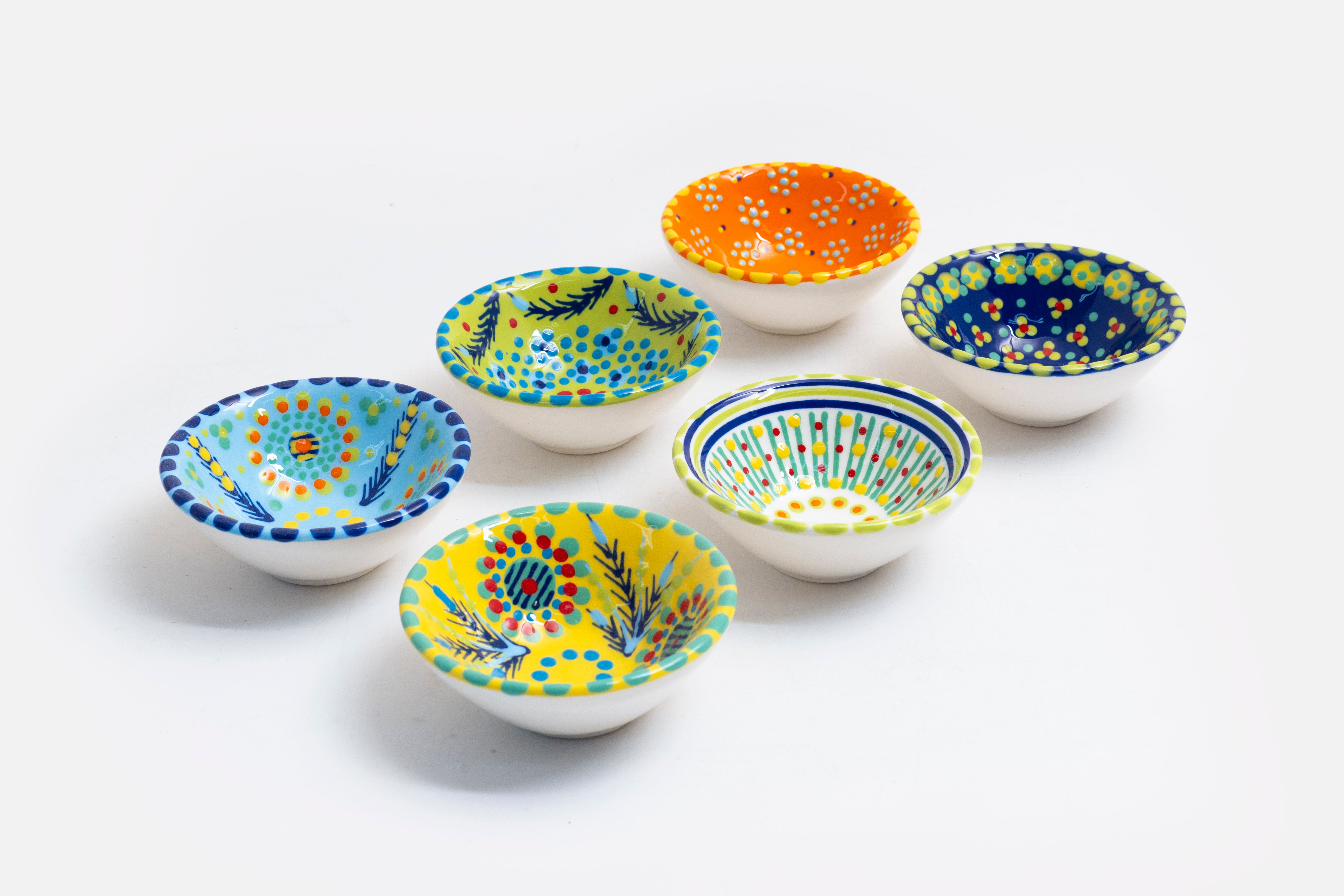 Tiny bowls in various background colors; baby blue, lime green, orange, indigo, white & yellow.  Painted with sweet designs of flowers, dots, stripes in contrasting colors.