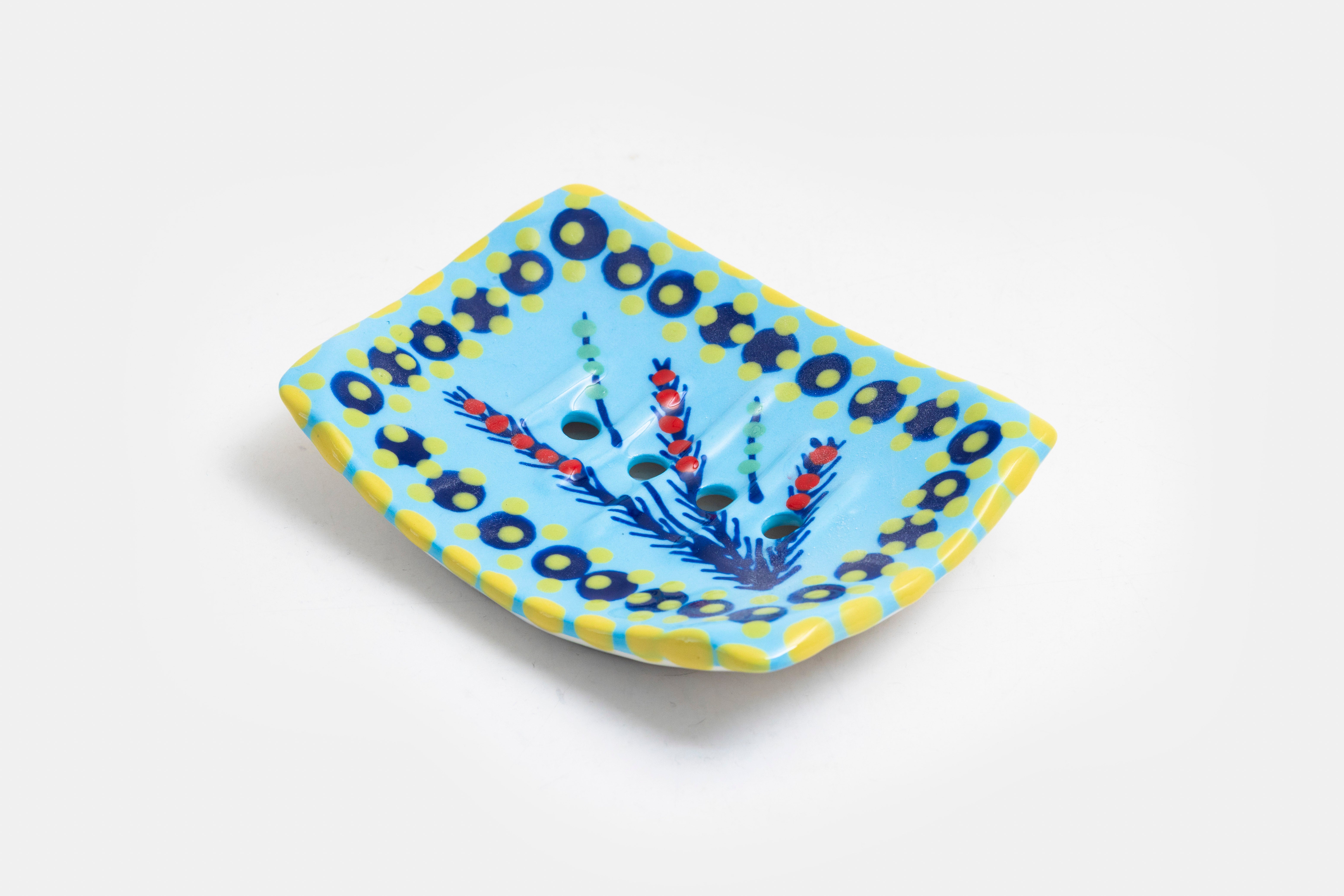 Ceramic square soap dish with base color of baby blue. Flowery design with dots painted on top in lime green, turquoise, red and touches of orange. Drain holes in dish!