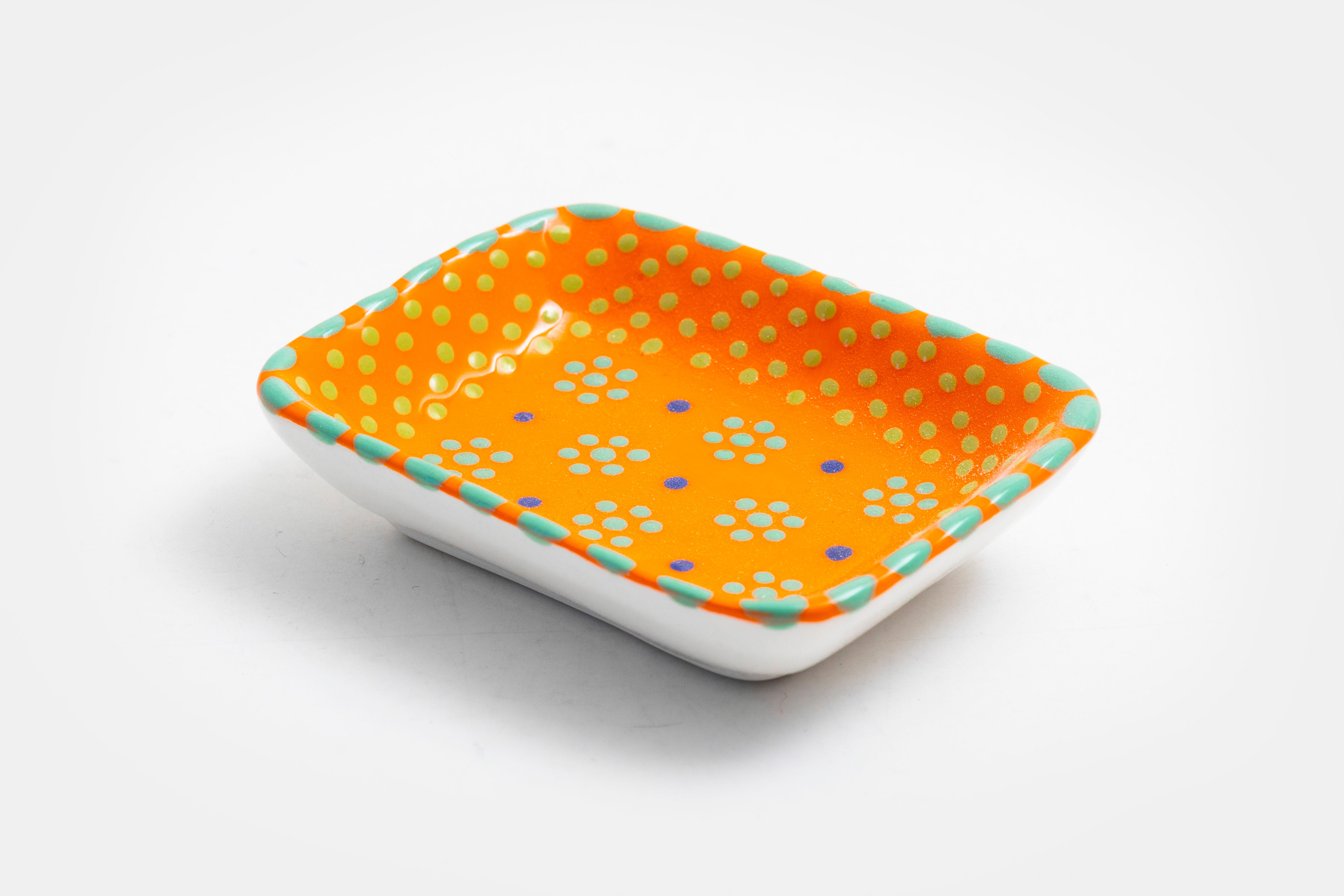 Ceramic rectangle shape Tiny Dish with  Orange base color. Dots & Stripes and flowers painted on top in yellow, red, blue and jasper green.