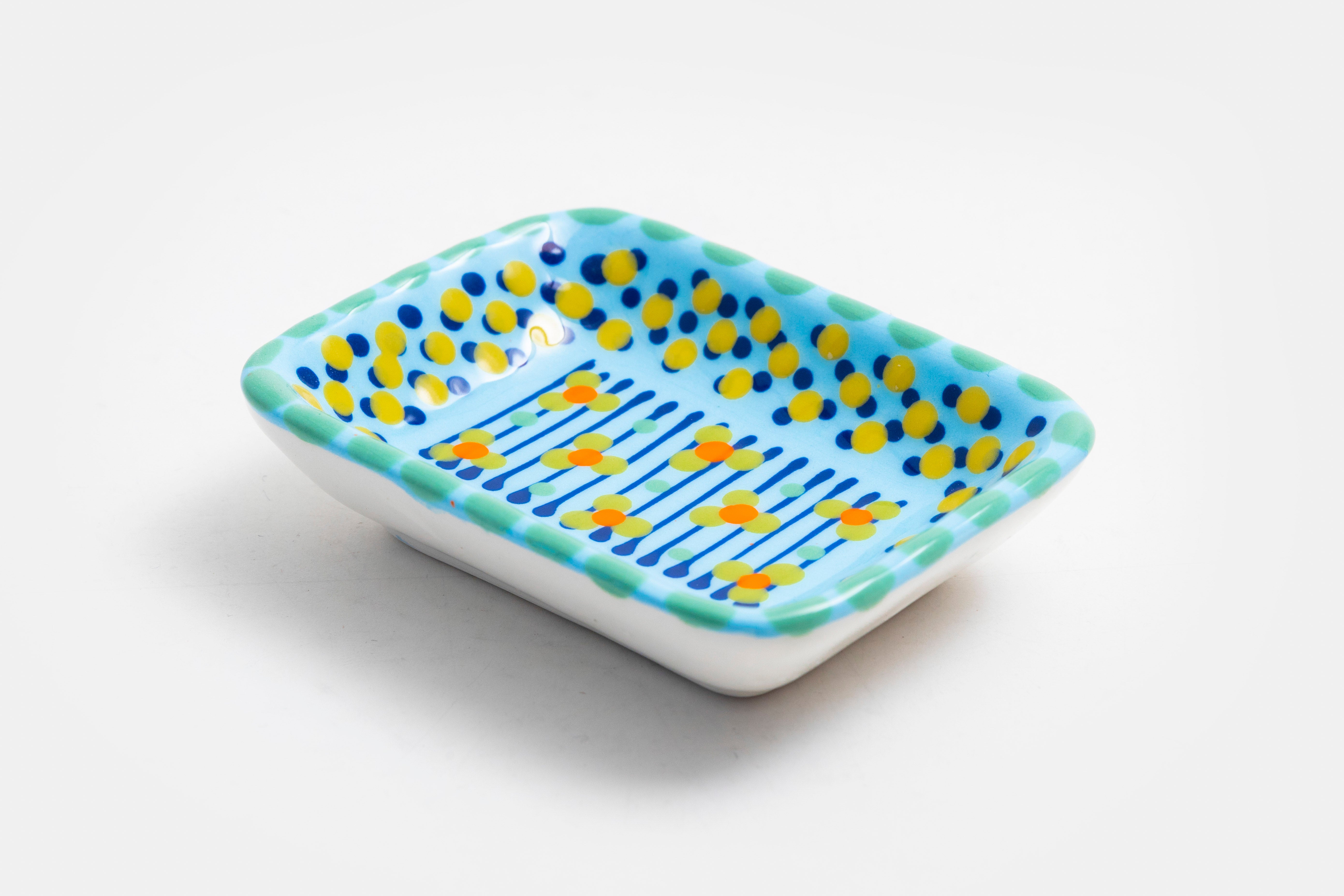 Ceramic rectangle shape Tiny Dish with Baby Blue base color. Dots & Stripes and flowers  painted on top in yellow, red, indigo, lime green and orange.