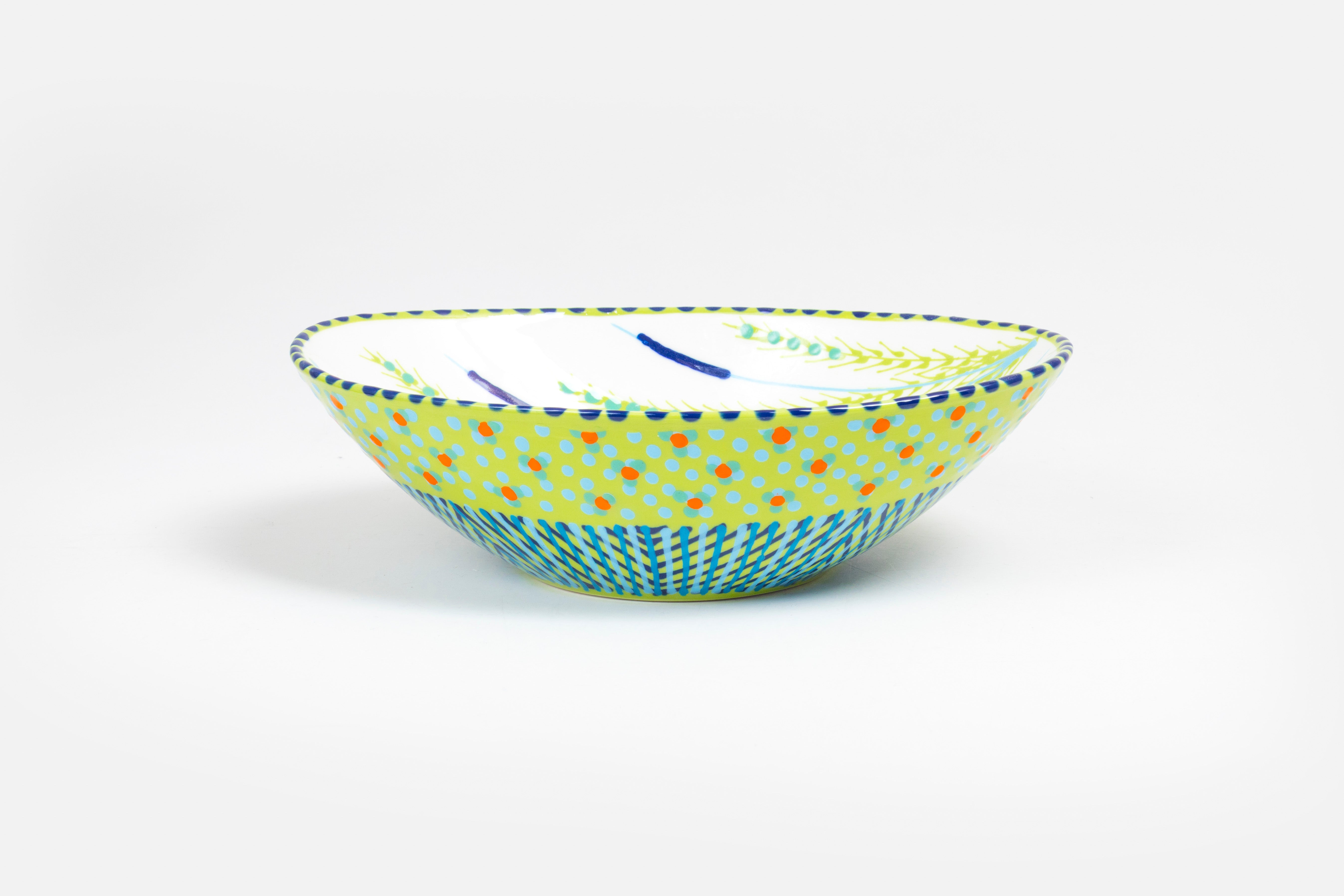 Oval ceramic serving bowl with lime green base color.  Orange, yellow, and green with touches of red in dots & stripes and flowers on top. Inside is white  'dot ' flowers design. Very lovely and fairly traded!