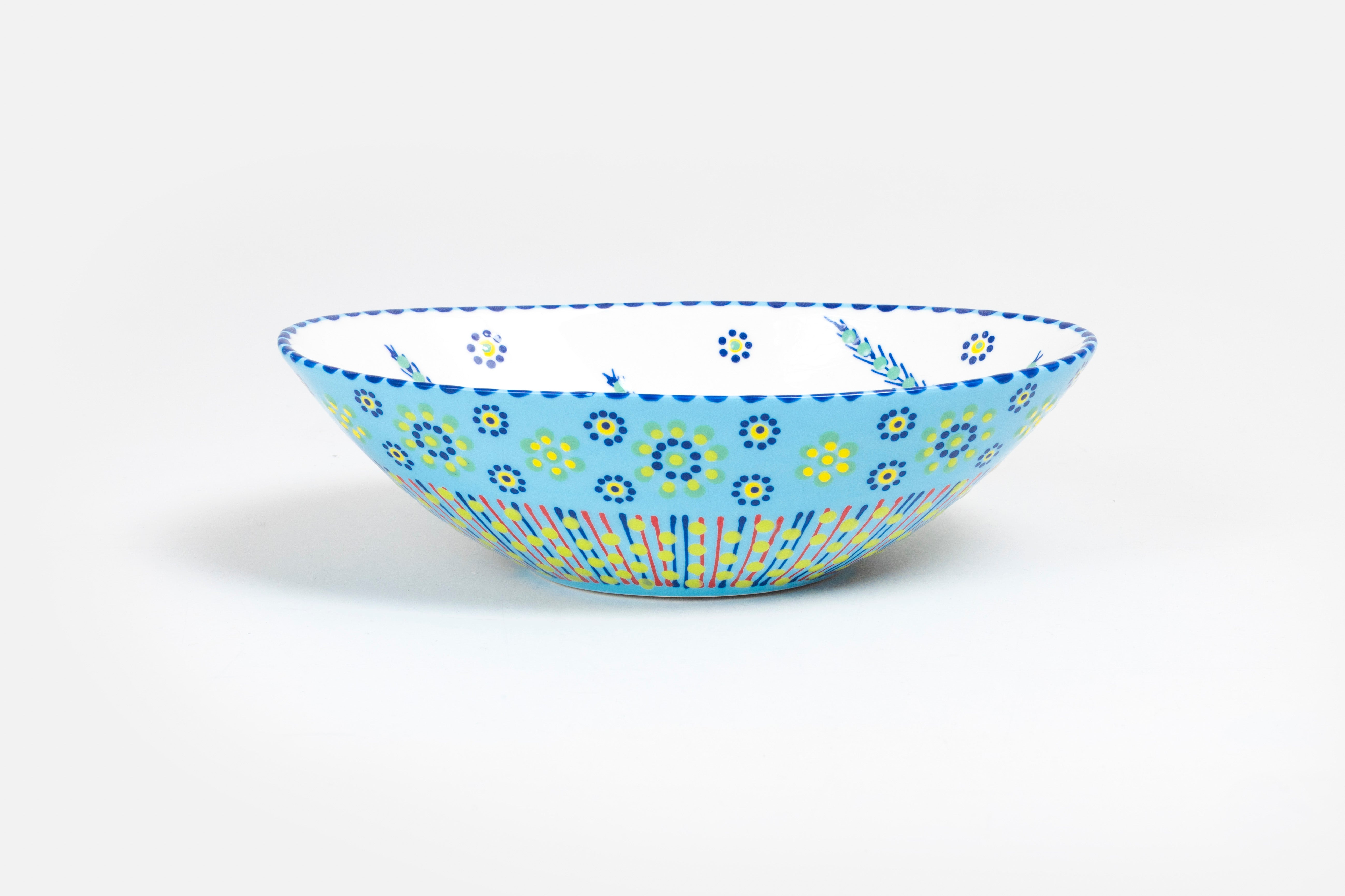 Oval ceramic serving bowl with baby blue base color.  Orange, yellow, and green with touches of red in dots & stripes and flowers on top. Inside is white  'dot ' flowers design. Very lovely and fairly traded!