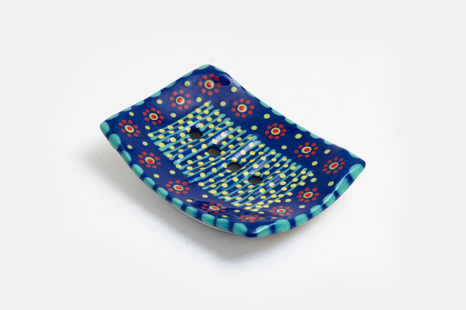 Ceramic square soap dish with base color of indigo blue. Flowery design with dots painted on top in lime green, turquoise, red and touches of orange. Drain holes in dish!