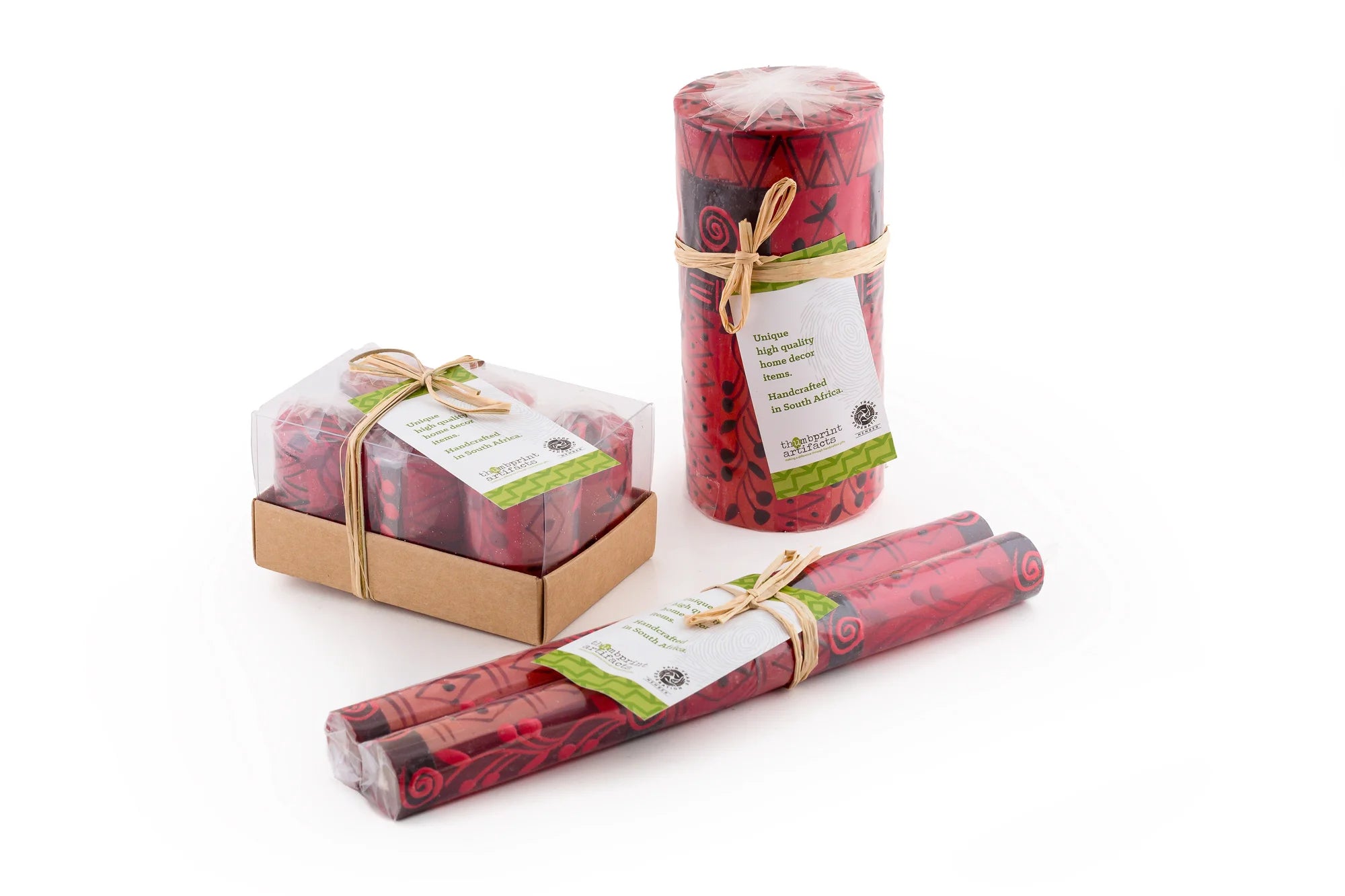 Berry Blaze candles in packaging; votives individually wrapped in a 6 pack box, pillar & cubes are individually wrapped and tied with story card, tapers are in a matched pair, individually wrapped and tied with a story card. All sustainable packaging.