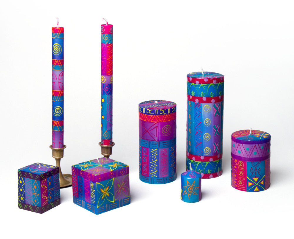 Blue Moon hand made and hand painted candle collection. Two candles cubes, candle taper pair, three pillars, and votive all painted in a pattern of colors of a Blue Moon; hews of blue, yellow, red, and pink.
