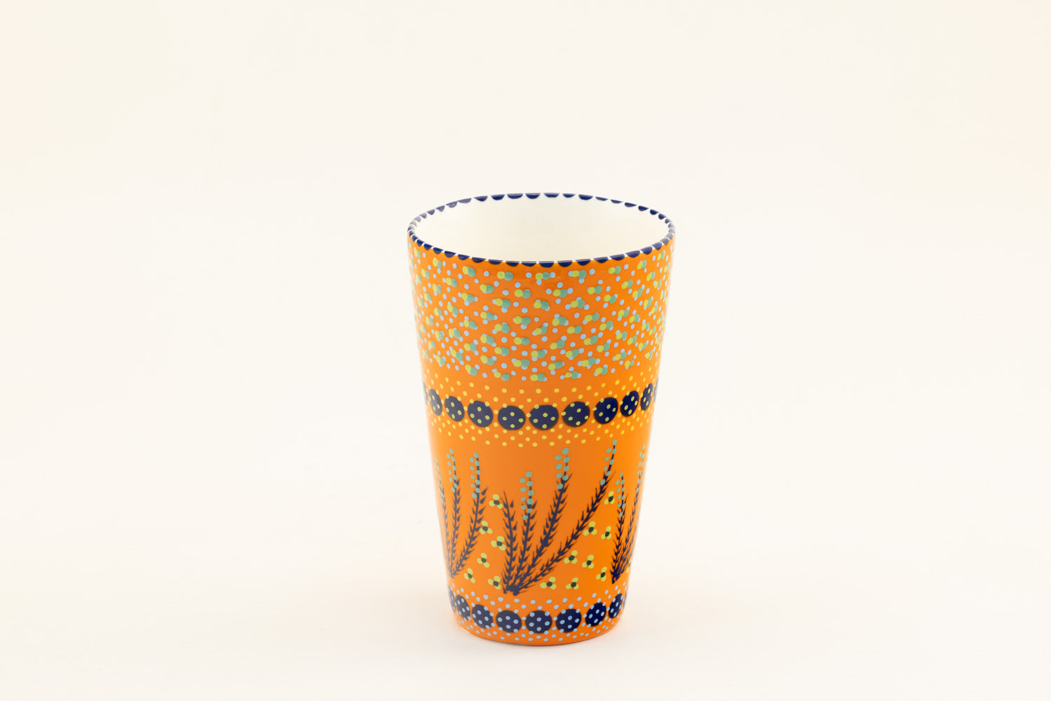 Ceramic vase with background color of orange.  Dots, stripe and flowers make the colorful designs on the background colors. 8.8" tall x 5.5" wide.