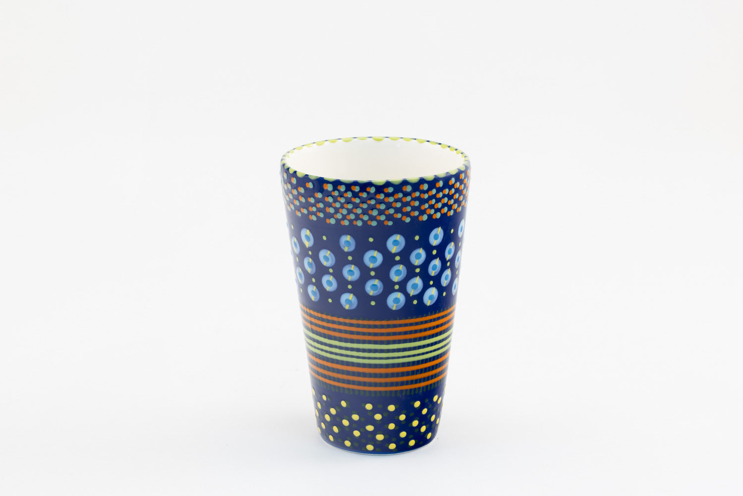 Ceramic vase with background color of indigo blue.  Dots, stripe and flowers make the colorful designs on the background colors. 8.8" tall x 5.5" wide.