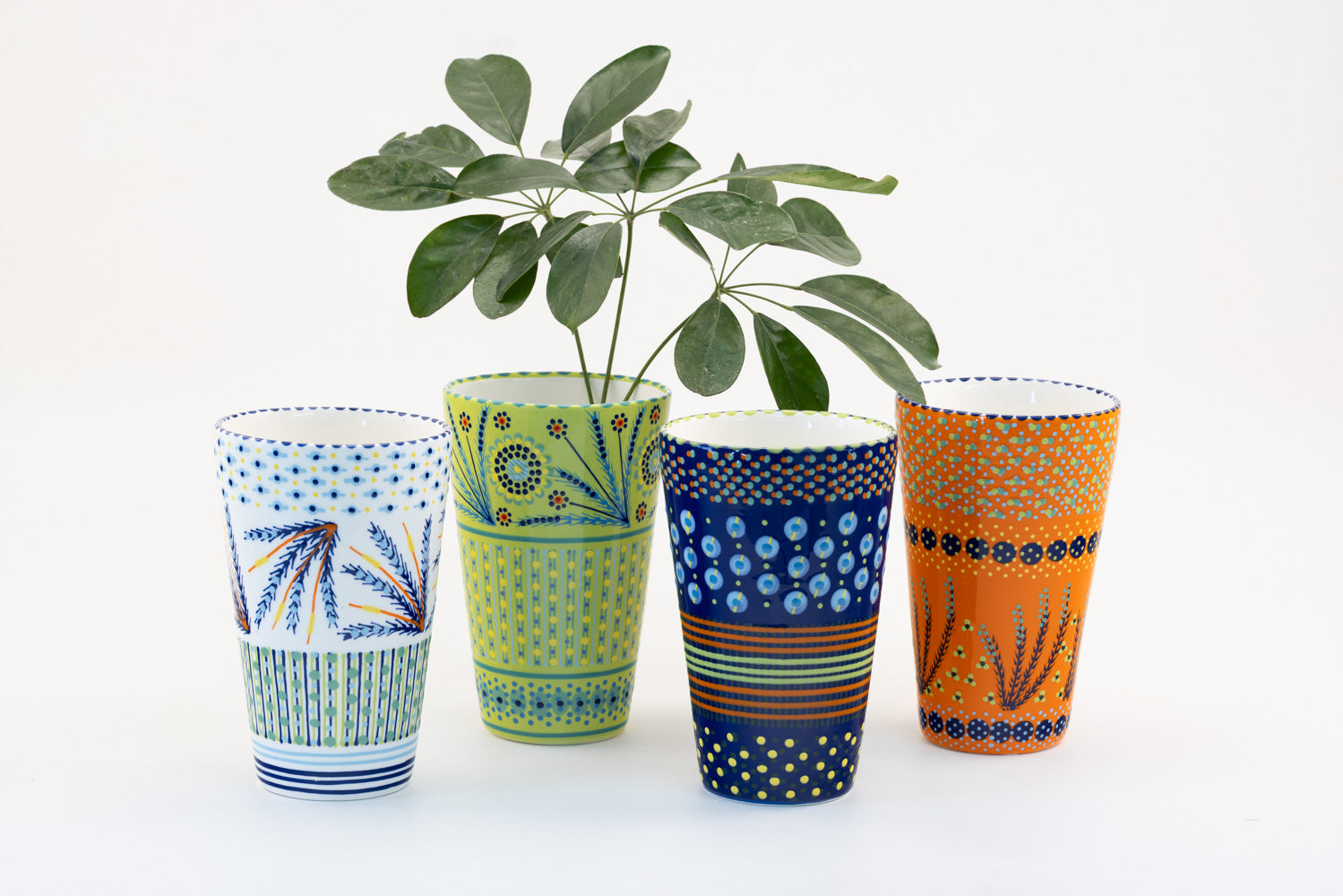 4 Classic vases with background colors of lime green, white, indigo blue, and orange.  Dots, stripe and flowers make the colorful designs on the background colors. 8.8" tall x 5.5" wide.