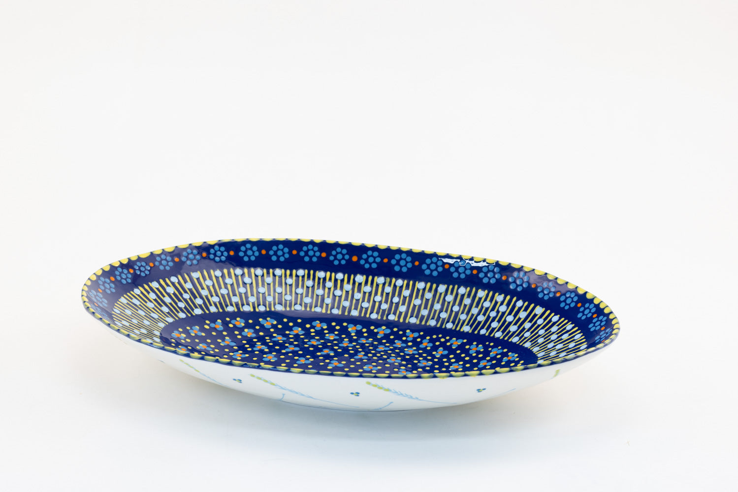 Indigo blue large oval serving bowl with dots, stripes and small flowers painted in baby blue, green and yellow. 15" x 8". Perfect to top off any table!