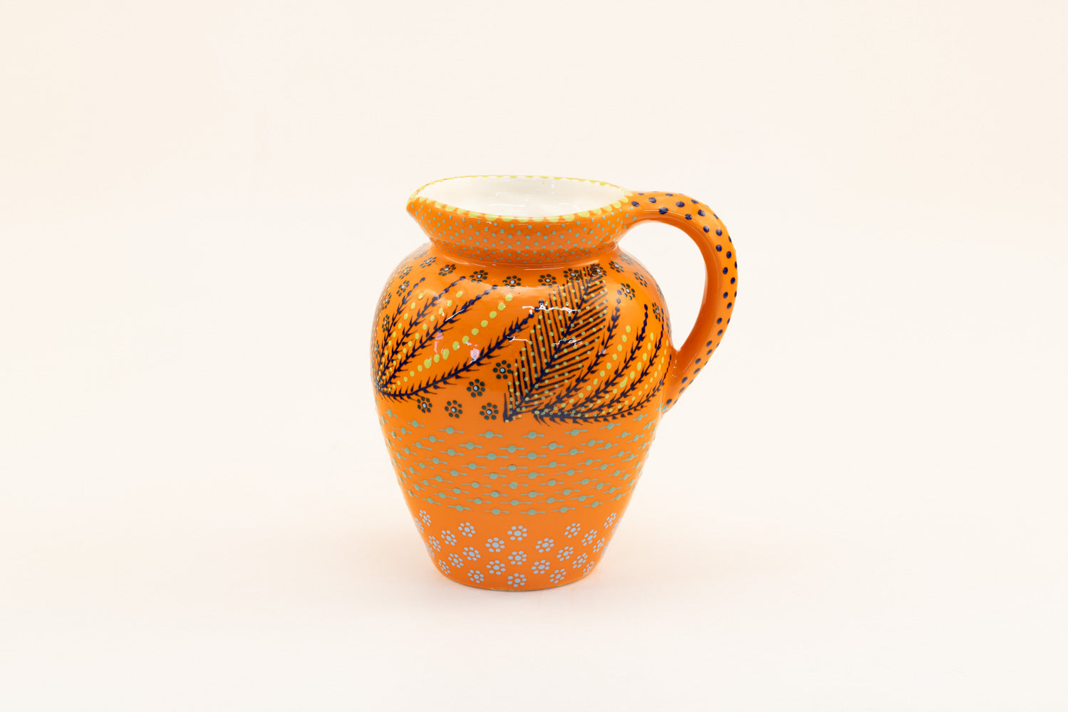 Classic water jug with background color of orange.  Dots, stripe and flowers make the colorful designs on the background colors. 9" tall x 5" wide.