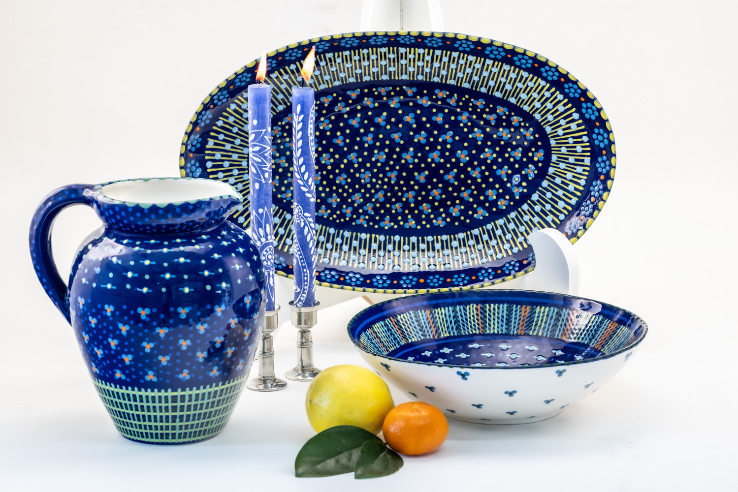 Beautiful Indigo blue water jug, large oval serving bow, and large round serving bowl  along side a water jug and pair of Henna white on blue taper pairs. Stunning collection
