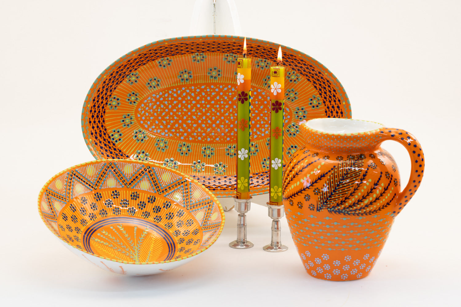 Wonderful orange water jug, large oval serving bowl, and large round serving bowl  with floral print in lime, baby blue and indigo. Along side a pair of Summer tapers.  Stunning collection