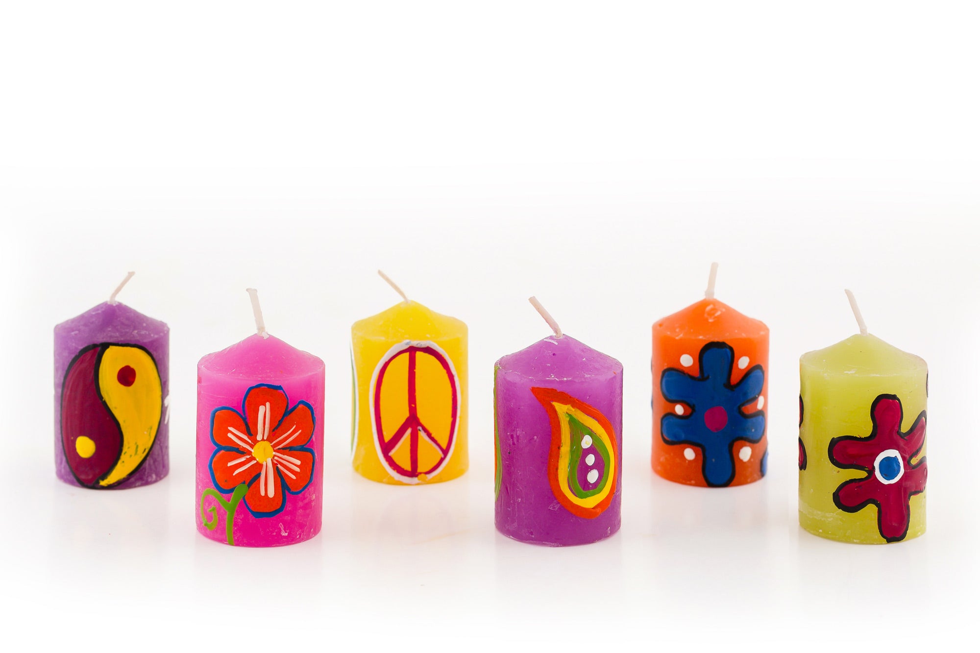 Selection of 6 votives; purple candle with ying-yang design, bright pink candle with orange flower, yellow candle with peace sign, purple candle with paisley, orange candle with blue 'hippie' flower, green candle with red 'pop art' flower.
