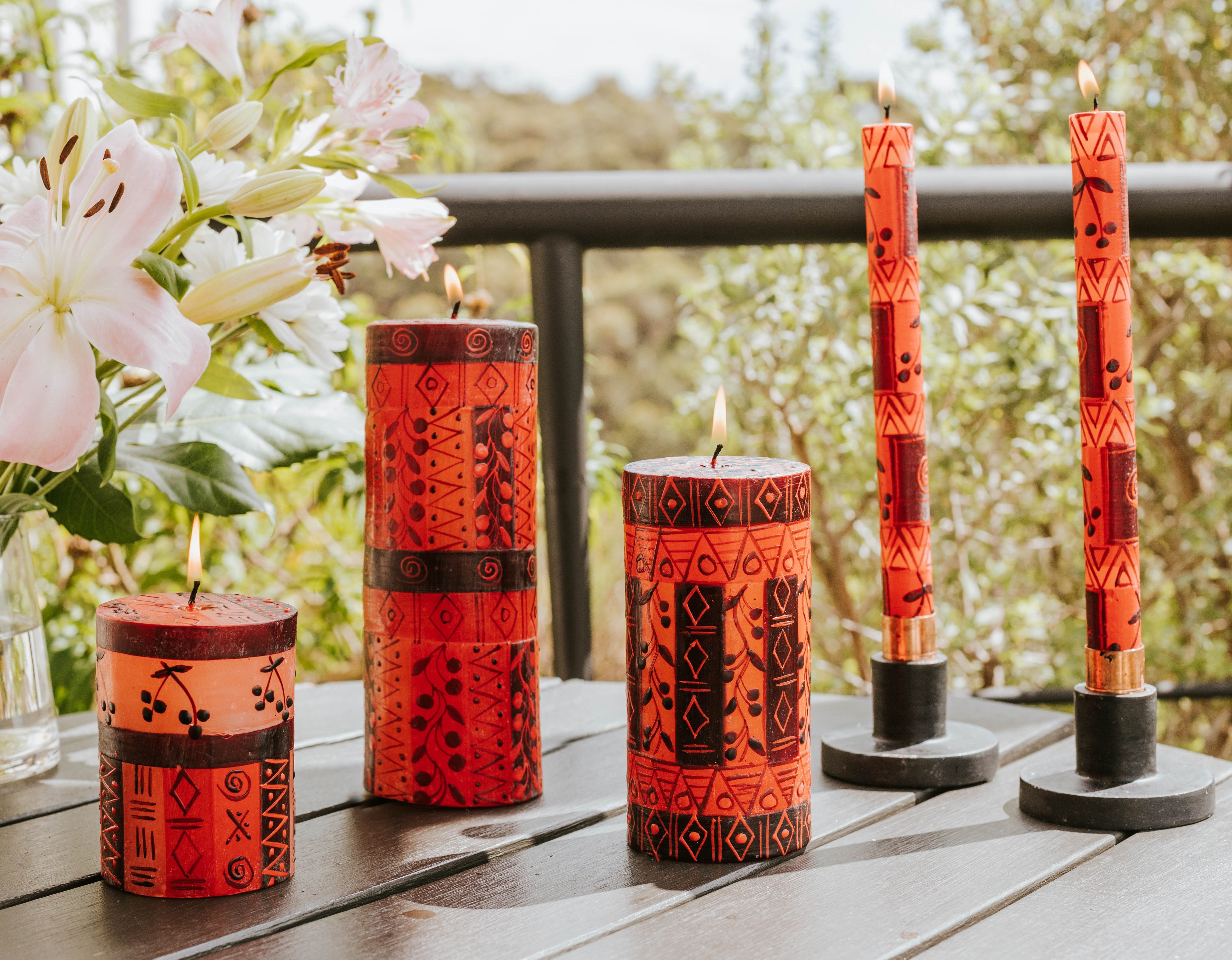 Sunny summer's day lifestyle photo of Berry Blaze pillars and tapers on a table burning brightly with lilies at the side! Just lovely!