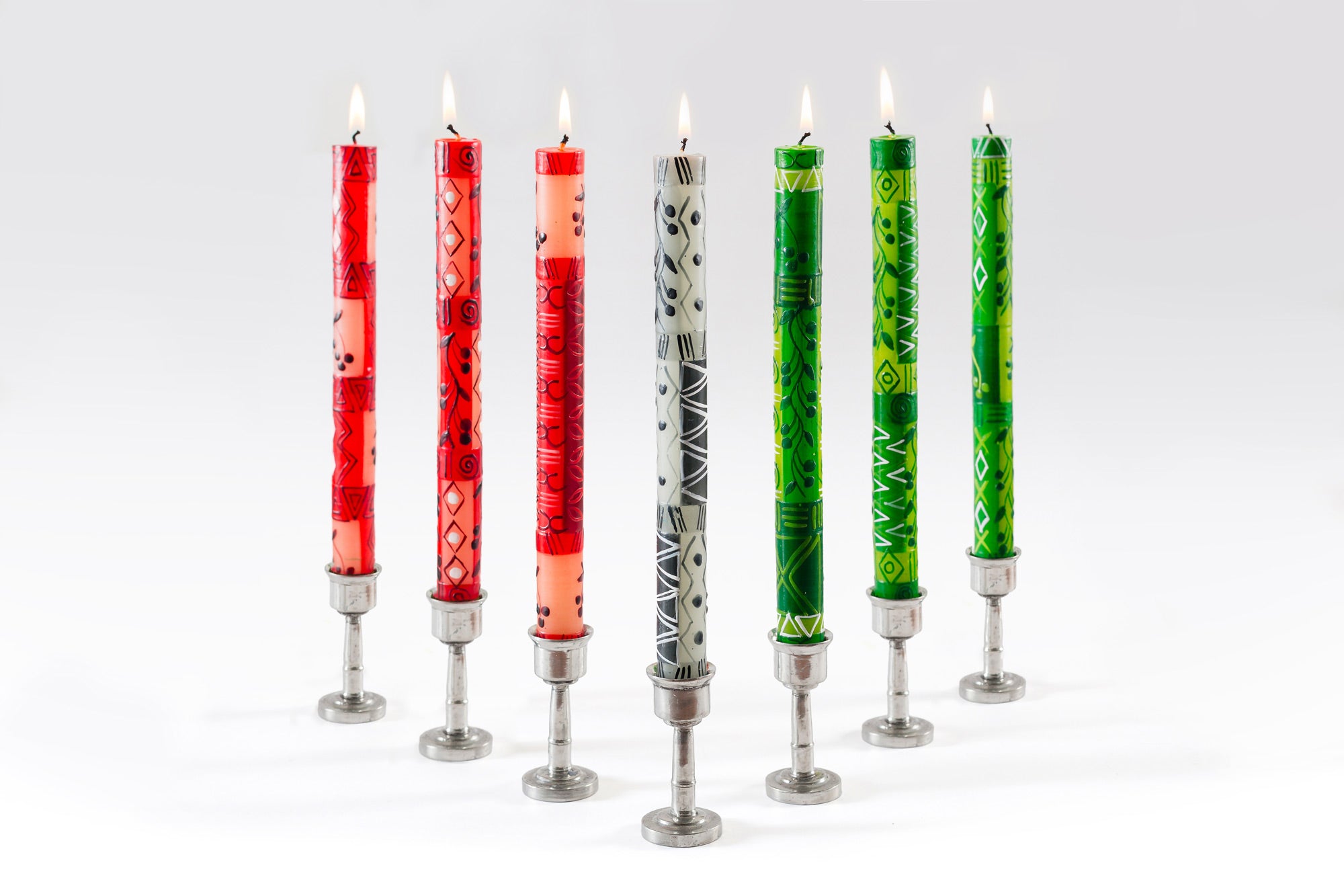 The Kwanzaa taper candle collection. Three red, one black & grey, and three green taper candles, with a berry design on each. All displayed in black taper holders. Fair Trade home decor.