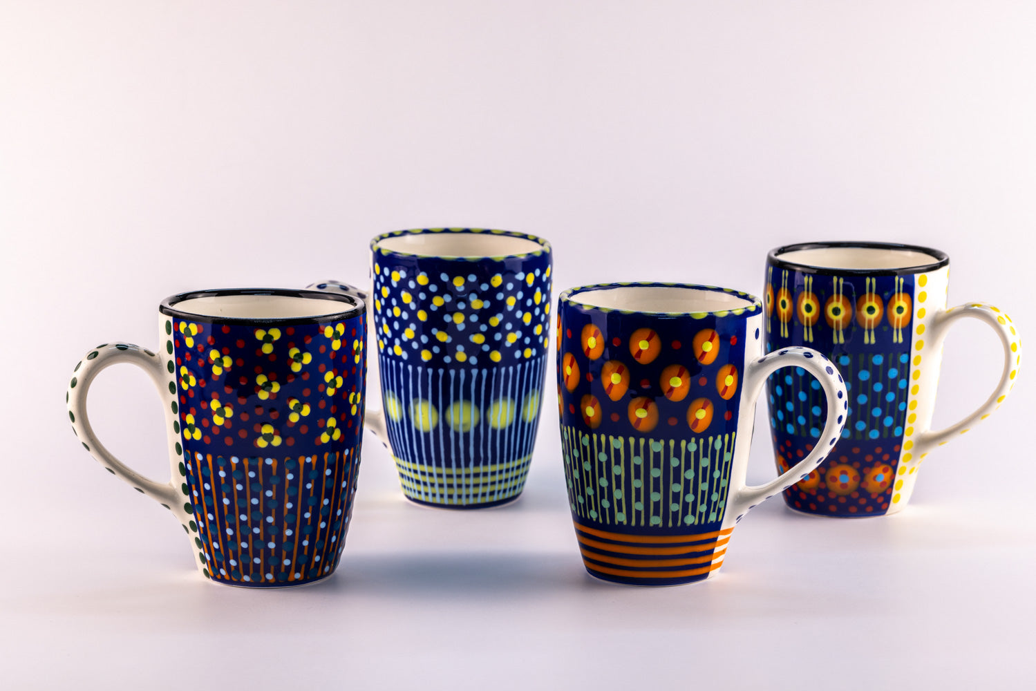 4 Colorful coffee mugs with Indigo Blue base color. Topped with dots & stripes in turquoise, orange, green, light blue, and yellow. Lovely!