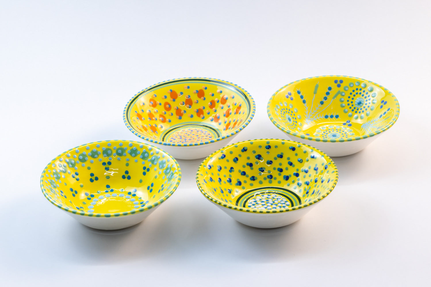 4 'nut' size ceramic bowls with yellow base color. Dots & Stripes painted on top in orange, jasper green & blue.