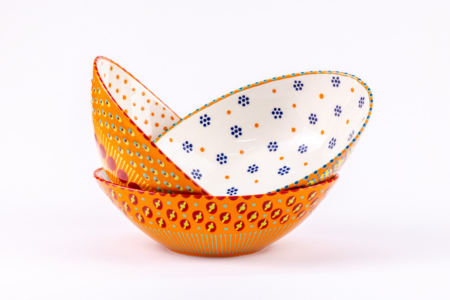 3 ceramic stacked oval serving bowls with Orange base color with dots & stripes on top in colors of red, yellow, orange, & green. Inside of one bowl is sweetly painted with blue 'dot' flowers and orange dots.