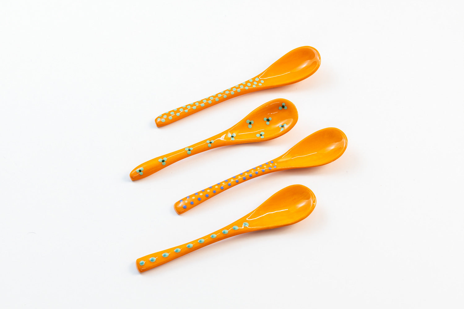 Small ceramic spoons with base color of Orange. Tiny dots & flowers painted on top in yellow, green, & light blue. So cute!