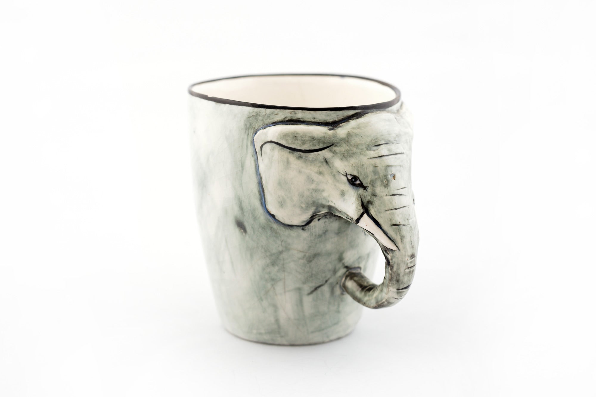 Ceramic mug painted in grey with an elephant head on the side and his truck is the handle! Whimsy and fun.