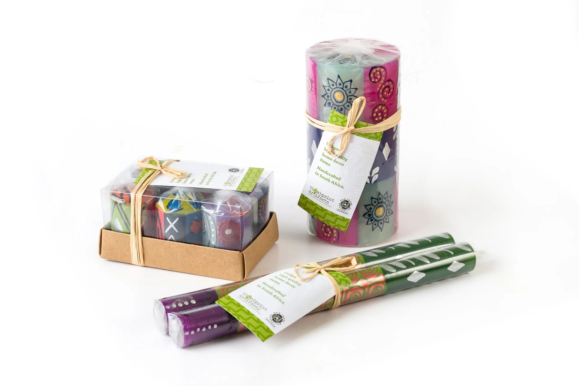 Sari votive 6-pack, taper pair, and 3" x 6" pillar in packaging; clear wrap with story card tied on with raffia. Perfect for gifting.
