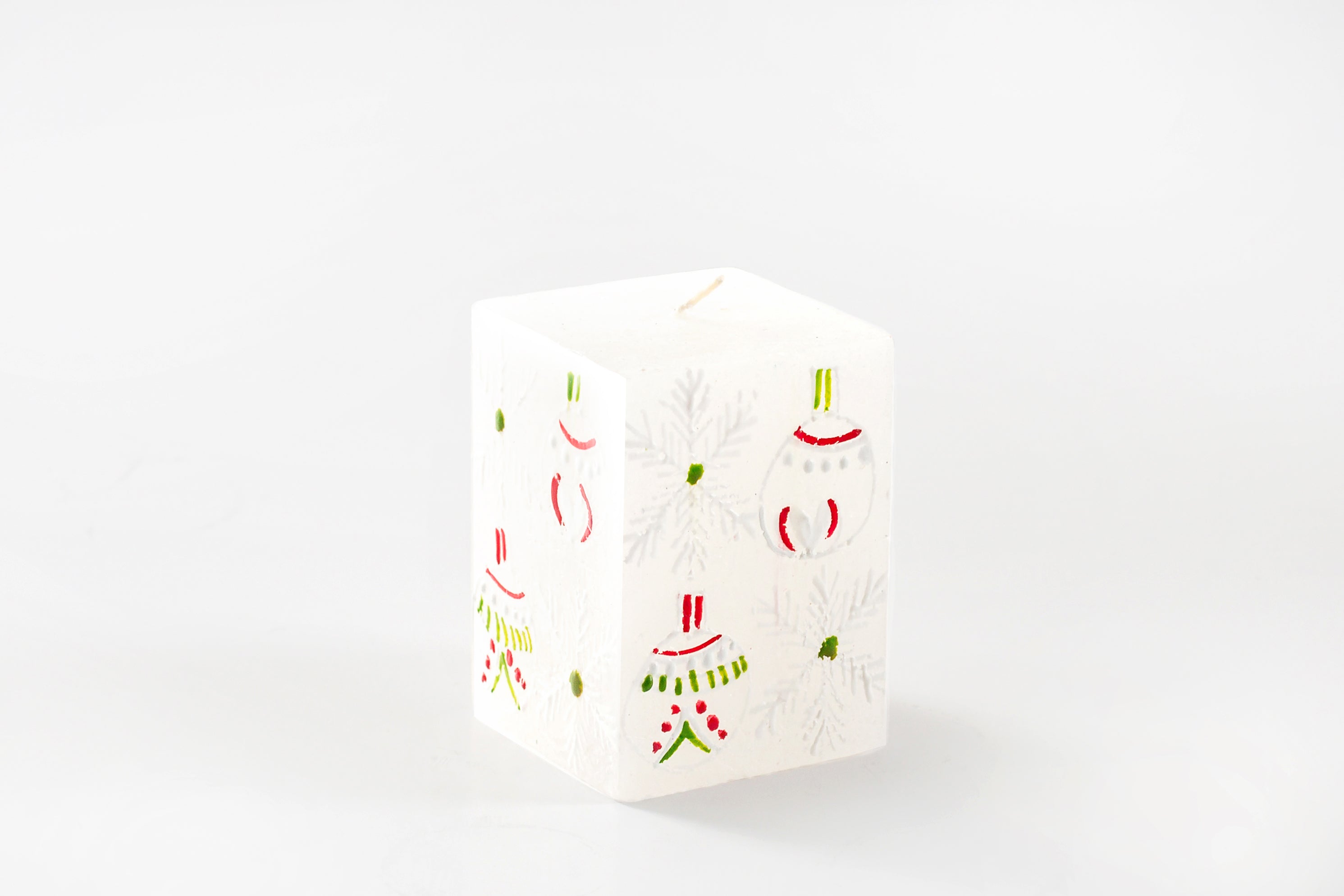 Whimsy Christmas 2" x 2' x 3" cubed candle. This one has a white base and hand painted with trees, snow flakes and Christmas ornaments painted in red, green and/or white.