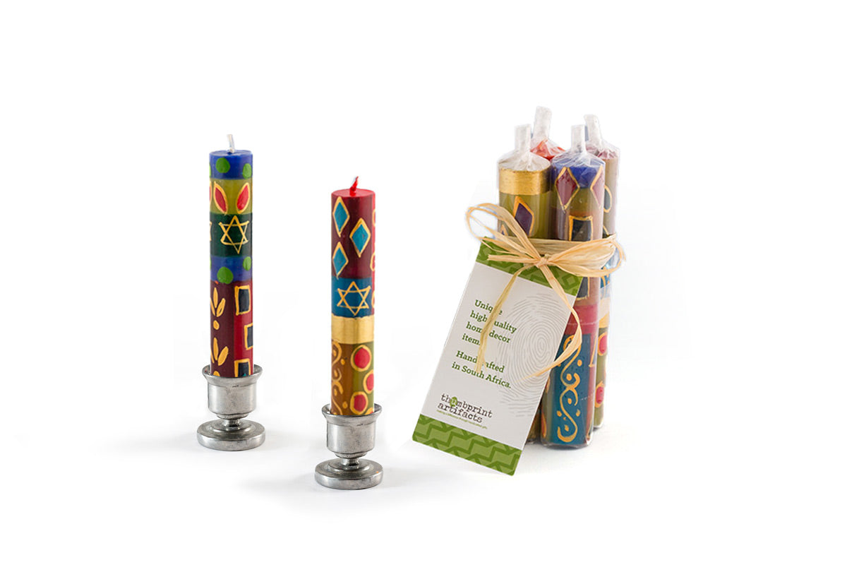 A pair of Judaica colorful with the star of David, Shabbat candles in pewter taper holders, with a pack of 4 tied together with a story card showing how these candles are sold in a gift pack.
