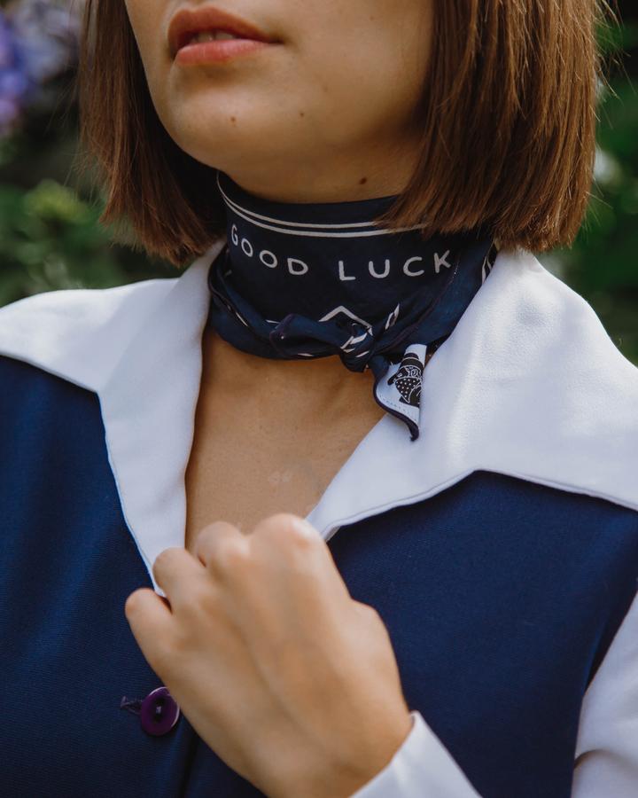 Woman showing how the bandana can be tied around the neck showing the message 'Good Luck'