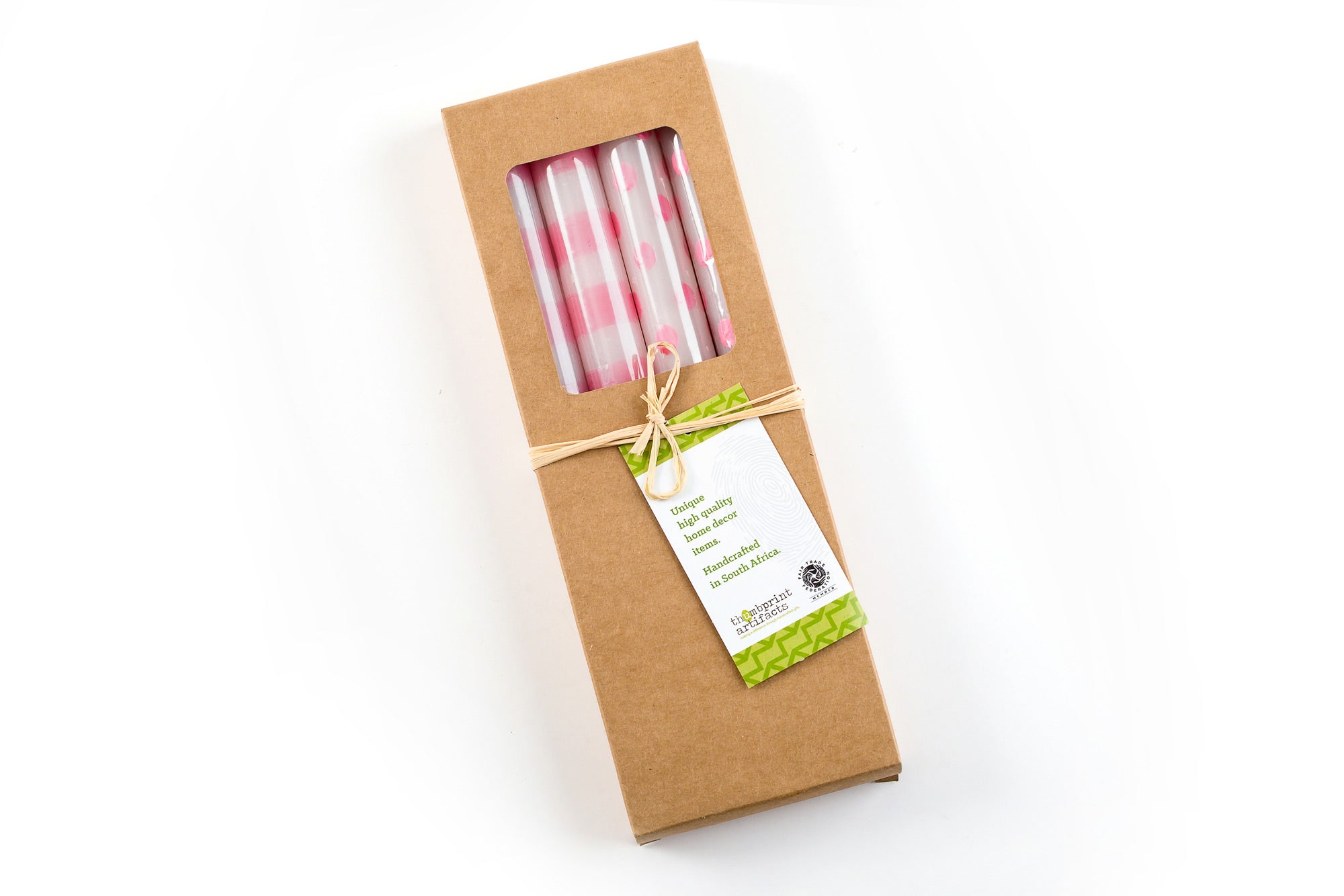 4 taper candles in a kraft paper gift box; two are white taper candles with pink stripes. and two are white candles with pink dots. The box is tied with a story card.  Lovely gift & Fair Trade.