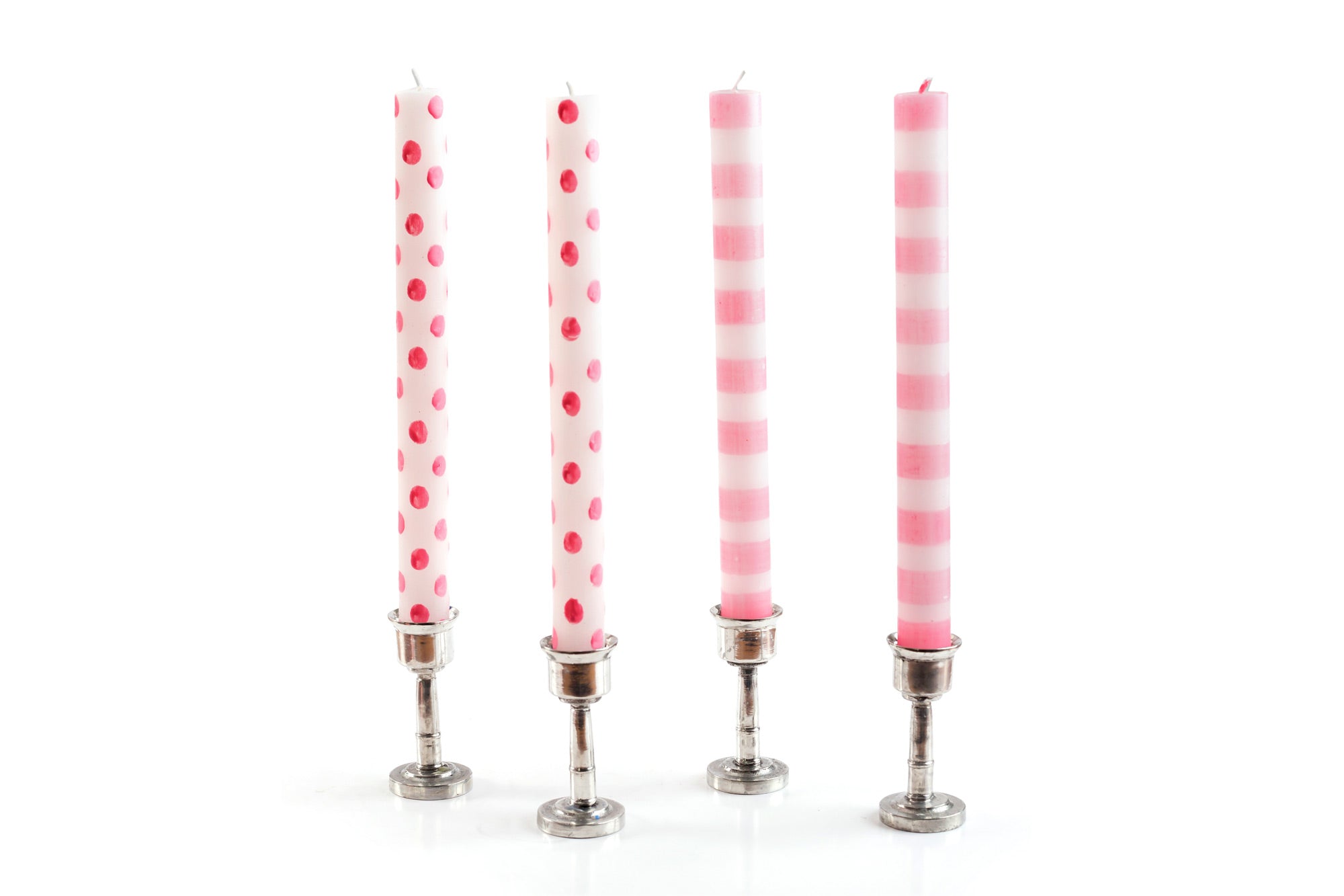 4 taper candles in pewter candle holders, two are white candles with pink dots, and two are white candles with blue dots.