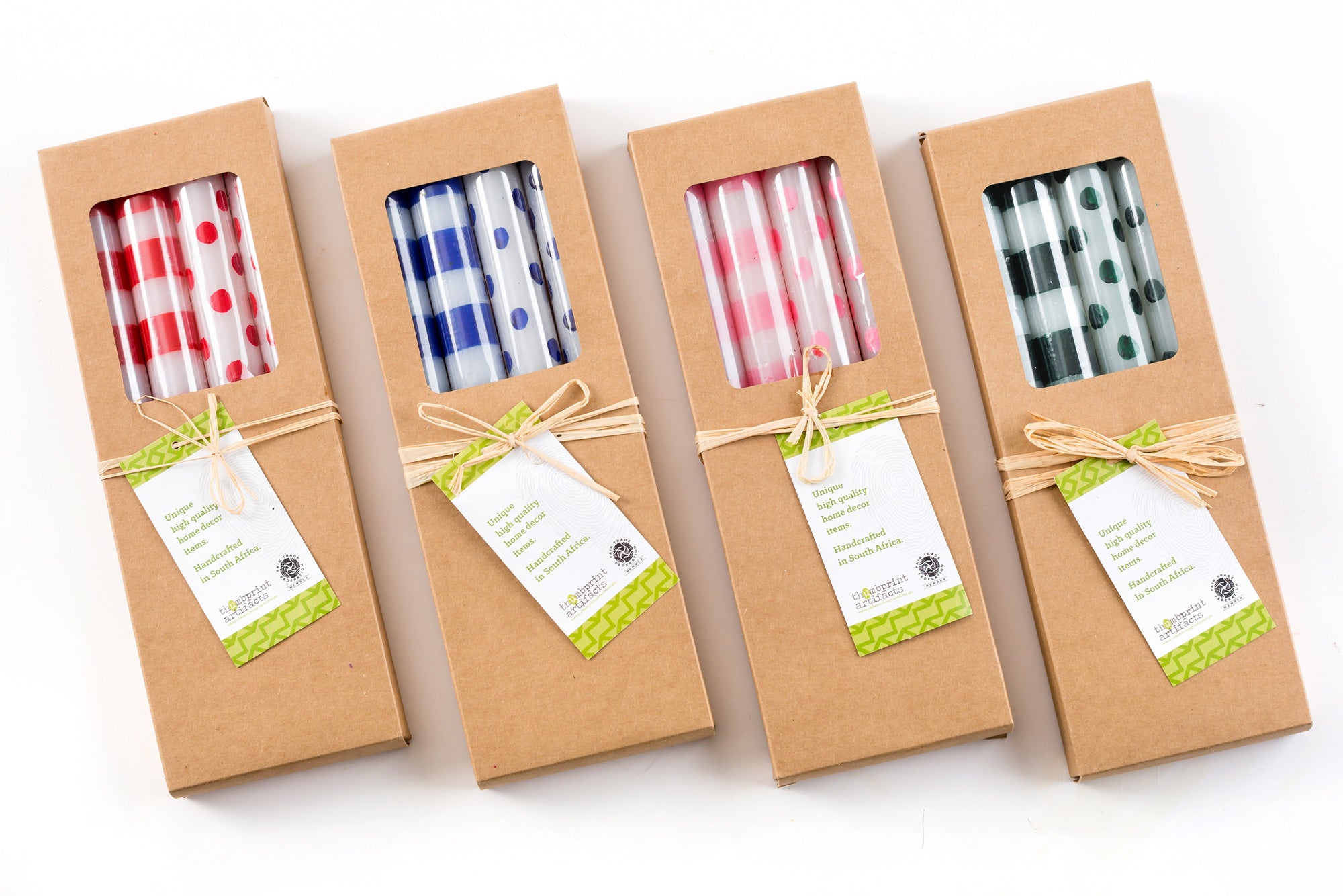 All four Dots & Stripes gift boxes of 4 taper candles; two with dots and two with stripes in the following colors; red, blue, pink, and green. Each box is tied with a story card.