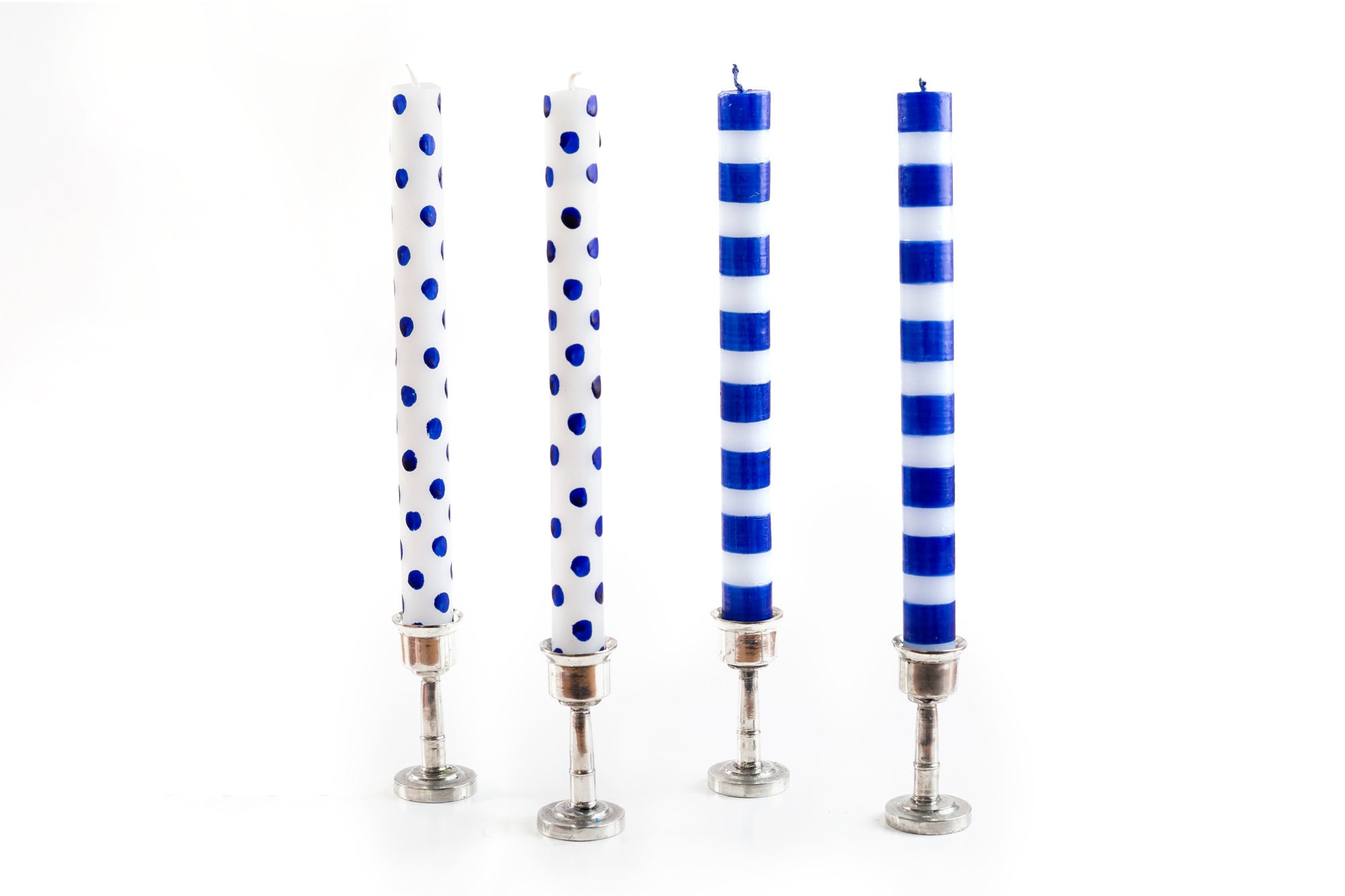 4 taper candles in pewter candle holders.  Two are white with blue dots and two are white with blue stripes. 