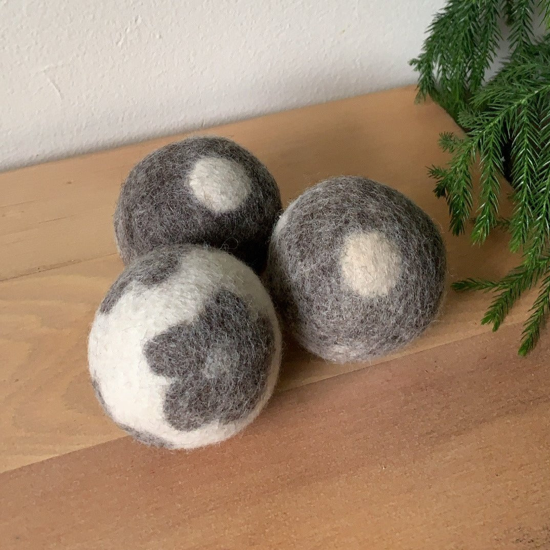 Fun felt dryer balls in three designs; cream with flower, brown with dot, and cream with stripe.
