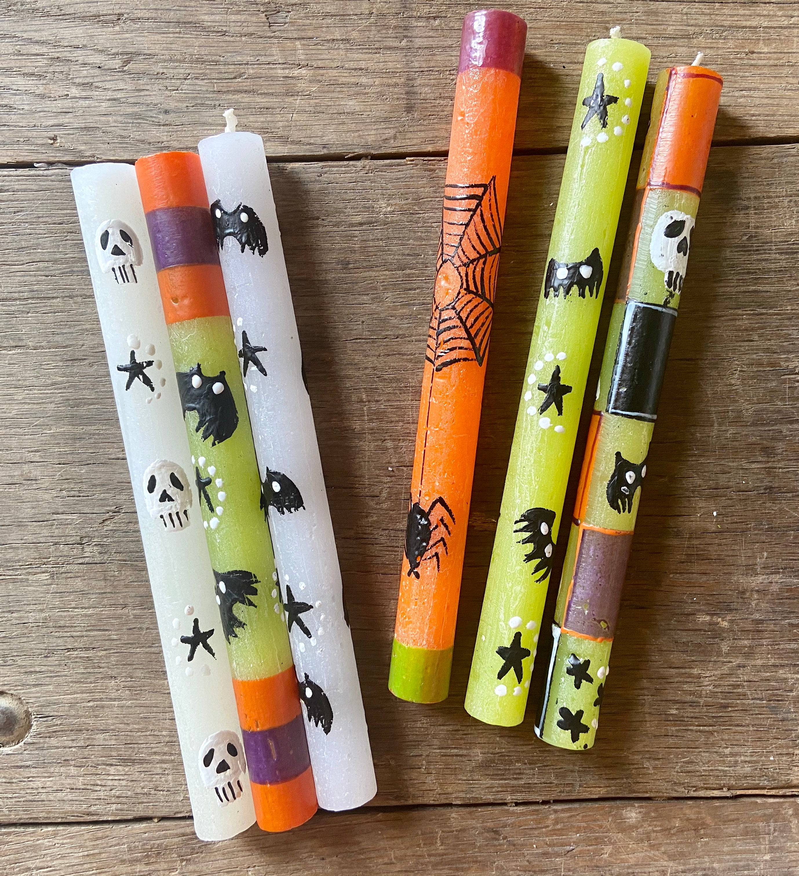 Halloween hand made & hand painted taper candles.  Fun Halloween designs; white taper candle with skulls & bats, green taper candle with bats and orange & dark purple stripe, orange taper candle with spider nest and spider climbing up to it!  Fair trade products.