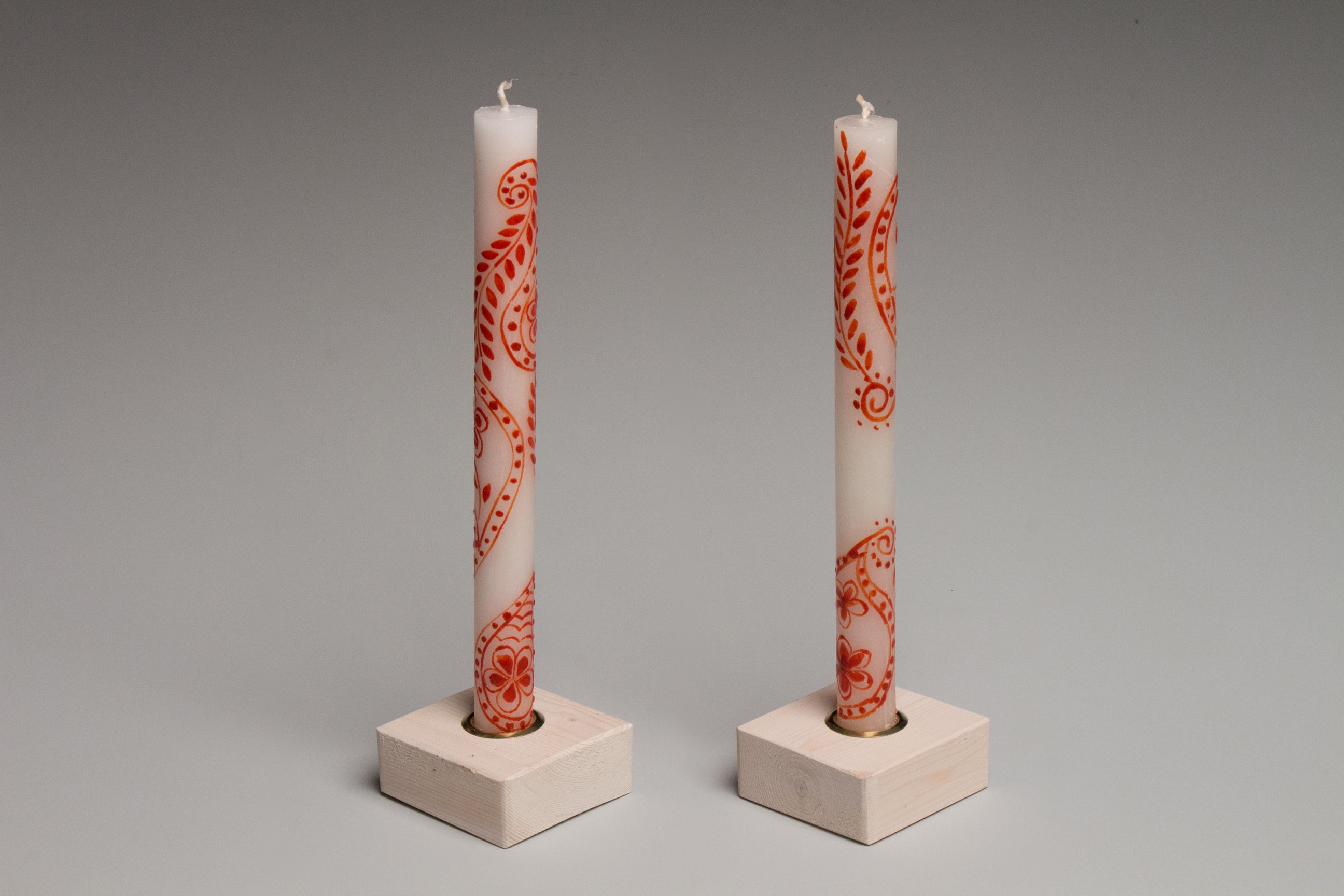 White wash color taper candle holders holding a pair of Henna Red on White taper candles.