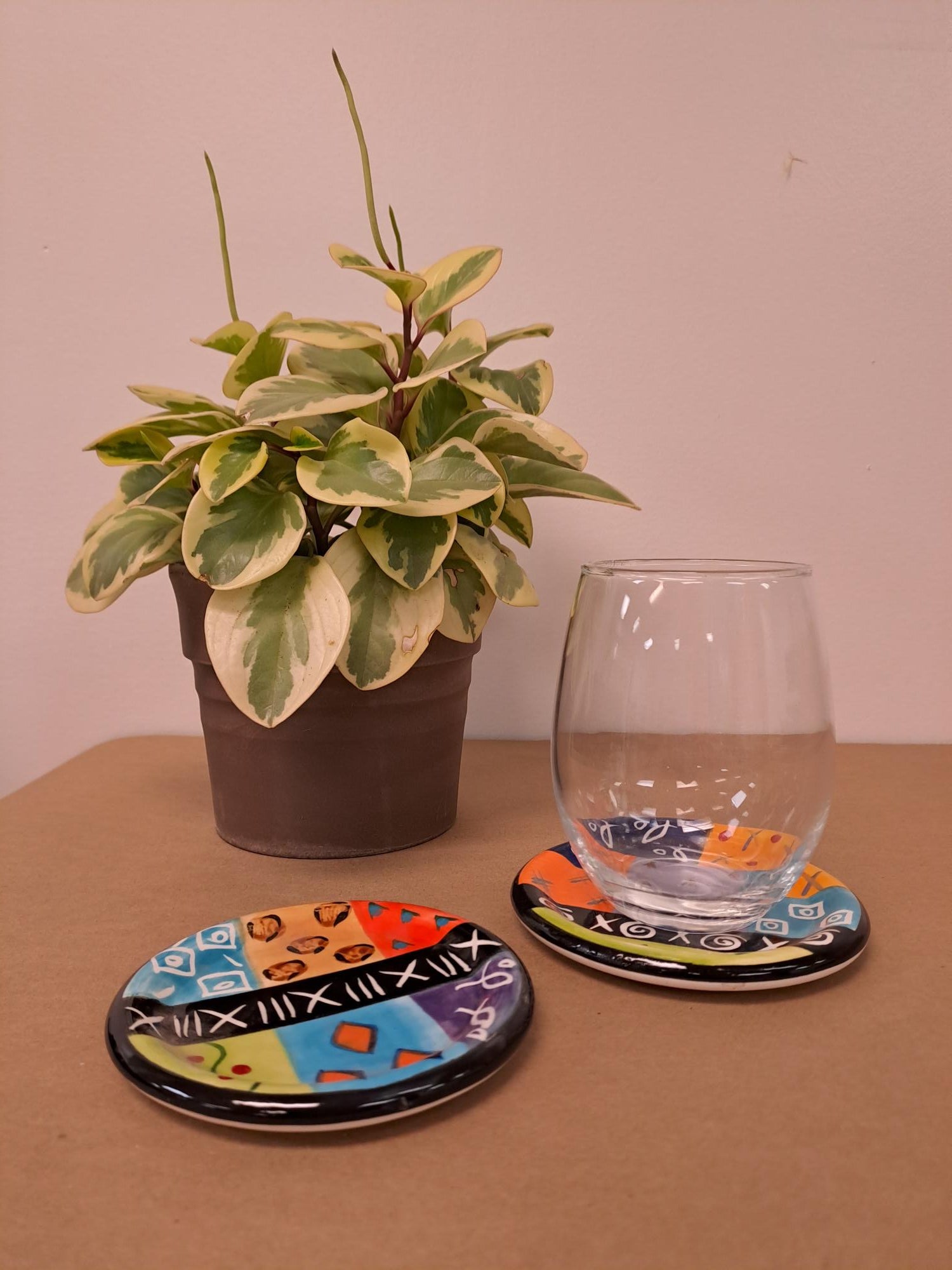 multicolor ethnic hand painted ceramic coasters showing how nicely a glass fits on the coaster.  Fun colors & designs of Africa.  Fair Trade.