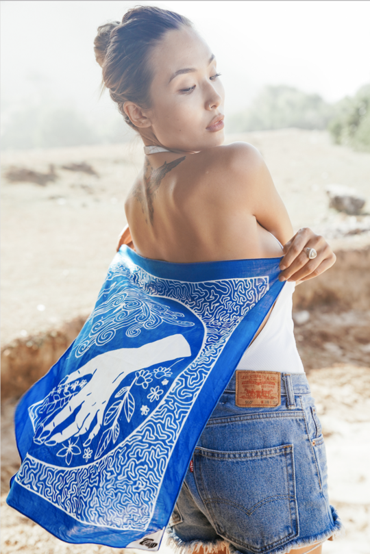 Woman displaying the Flow & Kindness bandana behind her back flowing after her.