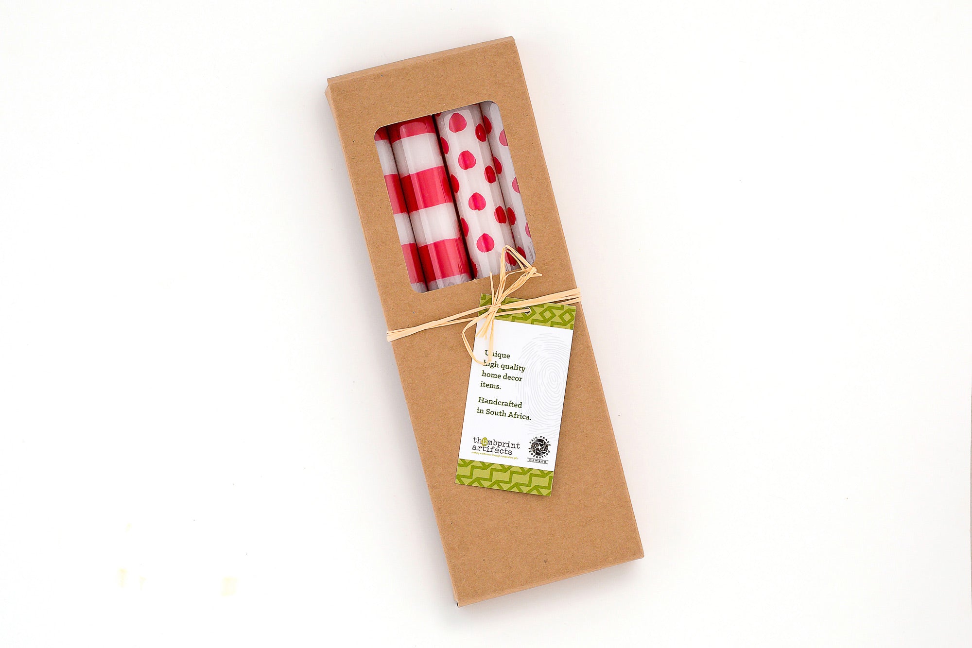 Four white tapers, two with red stripes and two with red dots, wrapped in a gift box of brown kraft with a story card.