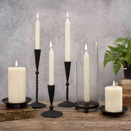 A grouping of white candles on various types of black candle holders. Included in the grouping is the Hurricane taper holder with a lite white taper candle.  Very lovely! 