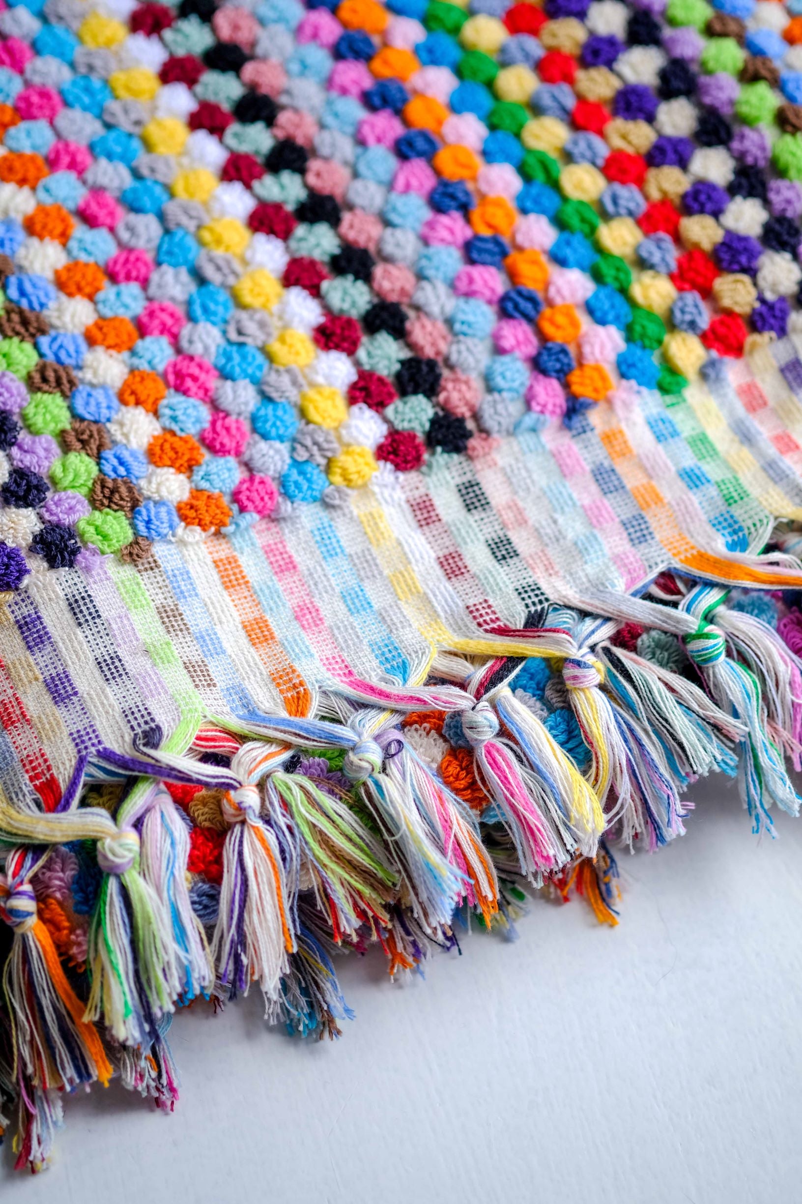 Close up photo of the hand woven towel with pompoms.  Colorful & very fun addition to your kitchen or bath!