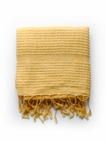 Folded yellow stone washed towel with tie fringe.