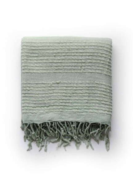 Folded light green stone washed towel with tie fringe.